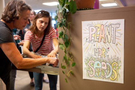 Two people browse through seeds packets stored in card catalog drawers