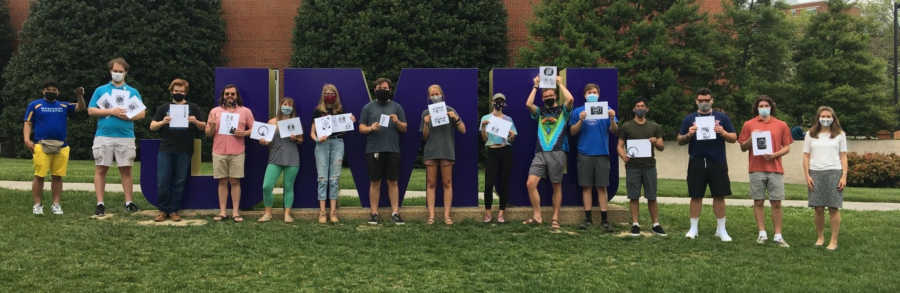 group photo of 14 students and professor holding up papers with images printed on them