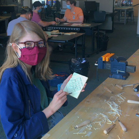 student holding linoleum block and carving tool