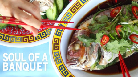 Title: Soul of a Banquet; Pictured: Cooked whole fish on a decorative plate with garnishes and hands holding brightly colored chopsticks