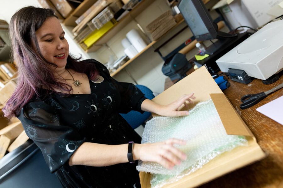 Photo of woman packing a book in a flat box for delivery.