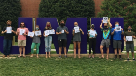 photo of 6 students standing in front of giant JMU letters holding their print designs from The Makery