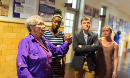 African-American woman presenting to a group of college students in front of panels showing old photographs