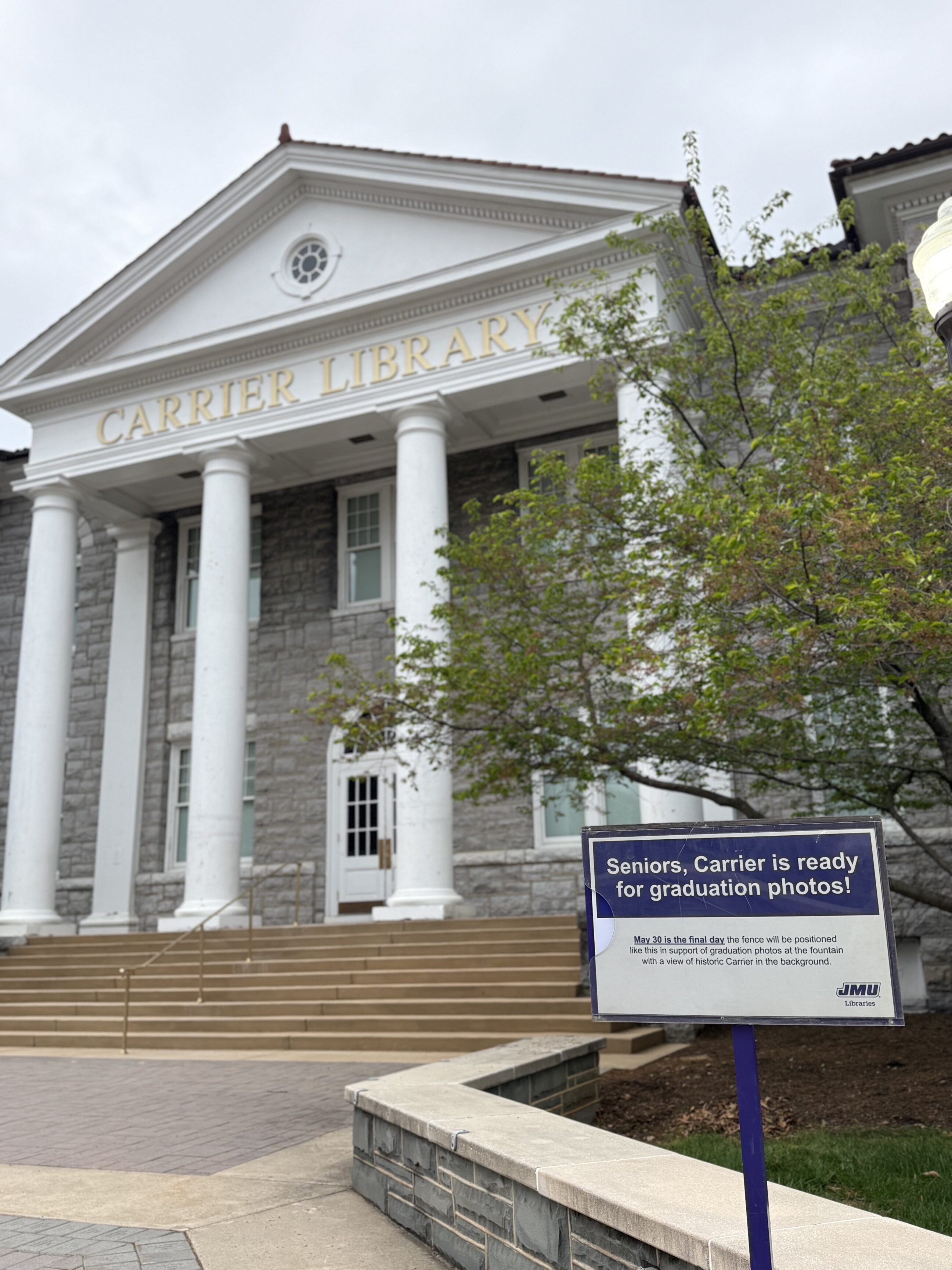 Photograph of the historic entrance of carrier library with a sign in front of it that says, "Seniors, Carrier is ready for graduation photos!"