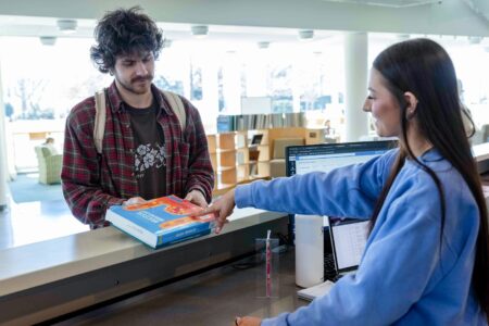 student picking up textbooks from a library desk
