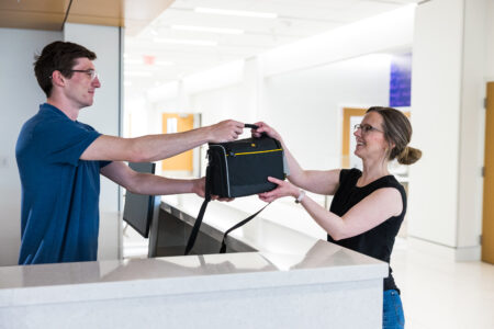 photo of staff member handing a camera bag to a patron